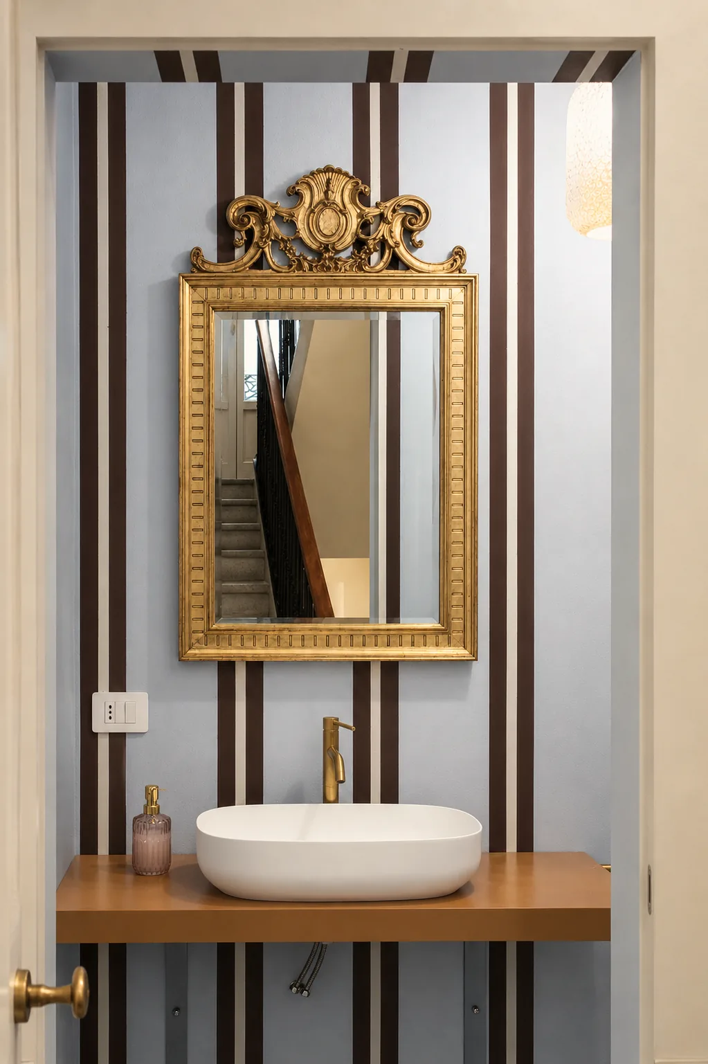 Washbasin beneath a gilt mirror in the mezzanine bathroom
