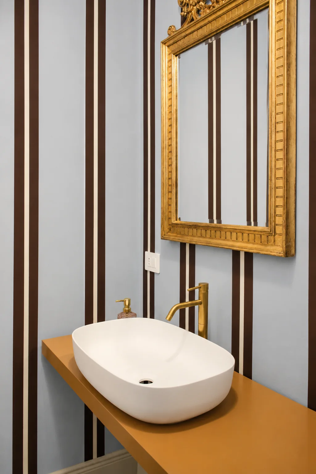 Washbasin, gilt mirror and striped walls