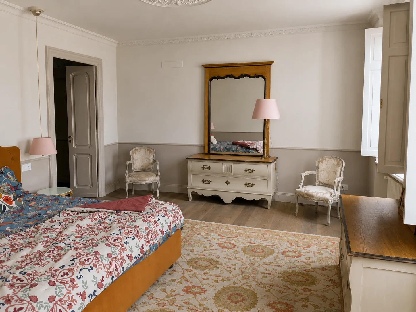 Generous bedroom with floral bed and antique furniture